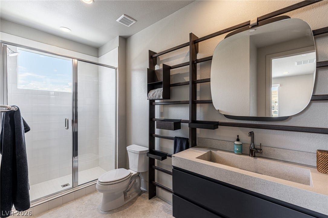 5216 Fading Sunset Drive, Las Vegas, NV 89135 A modern bathroom with sleek concrete counters and a large glass-enclosed shower.