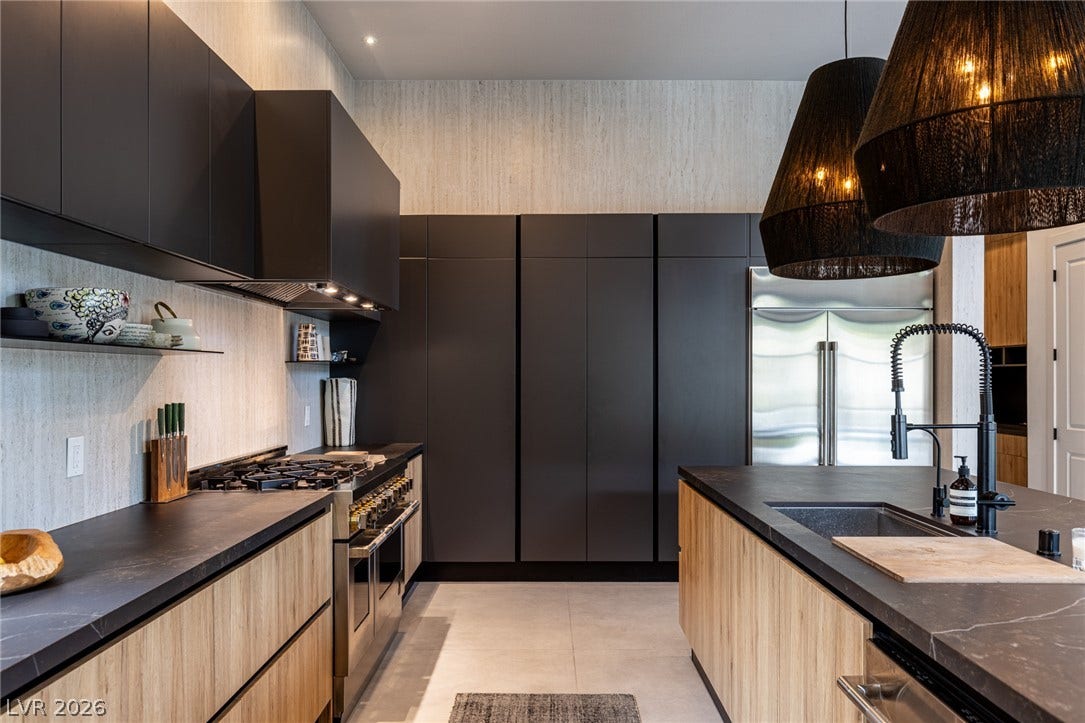 5216 Fading Sunset Drive, Las Vegas, NV 89135 Modern kitchen featuring sleek black cabinetry, stone countertops, and integrated appliances.