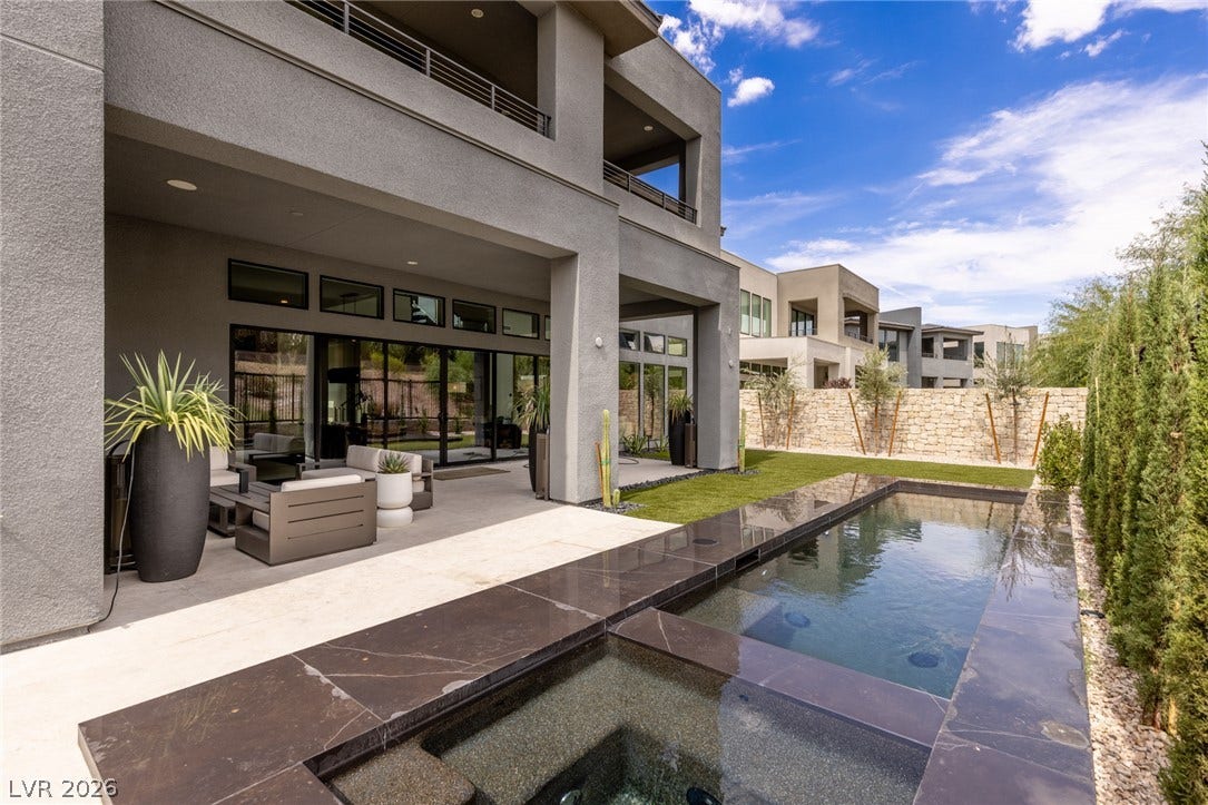 5216 Fading Sunset Drive, Las Vegas, NV 89135 A private outdoor oasis features a sleek pool and spa, flanked by a lush green lawn and an inviting patio.