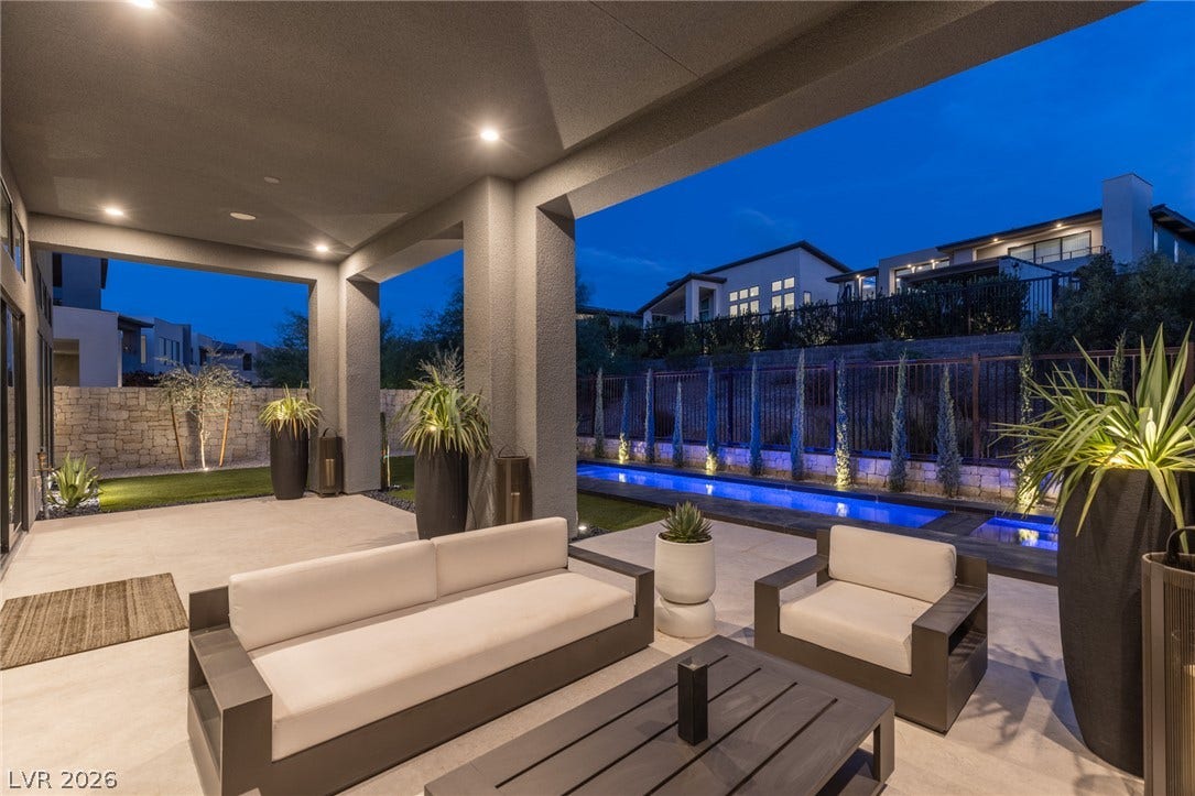 5216 Fading Sunset Drive, Las Vegas, NV 89135 An inviting covered patio featuring elegant recessed lighting overlooks a tranquil pool with illuminated water features.