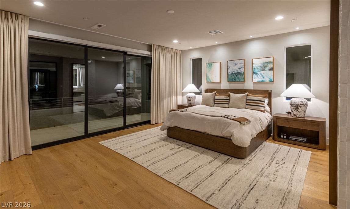 5216 Fading Sunset Drive, Las Vegas, NV 89135 Warm hardwood floors and recessed lighting enhance this bedroom with sliding glass doors.