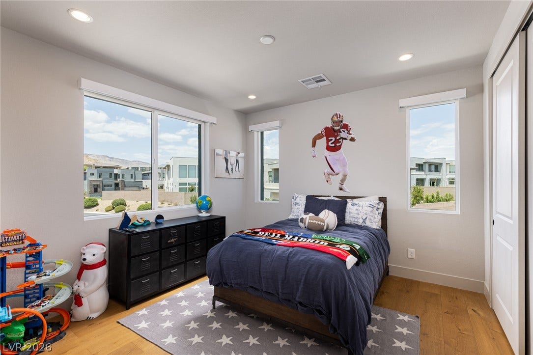 5216 Fading Sunset Drive, Las Vegas, NV 89135 A well-lit bedroom with warm wood flooring and ample natural light offers a pleasant and comfortable living space.