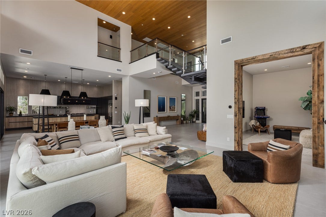 5216 Fading Sunset Drive, Las Vegas, NV 89135 A grand, open-concept living area features soaring ceilings, a modern staircase, and an inviting, neutral palette.