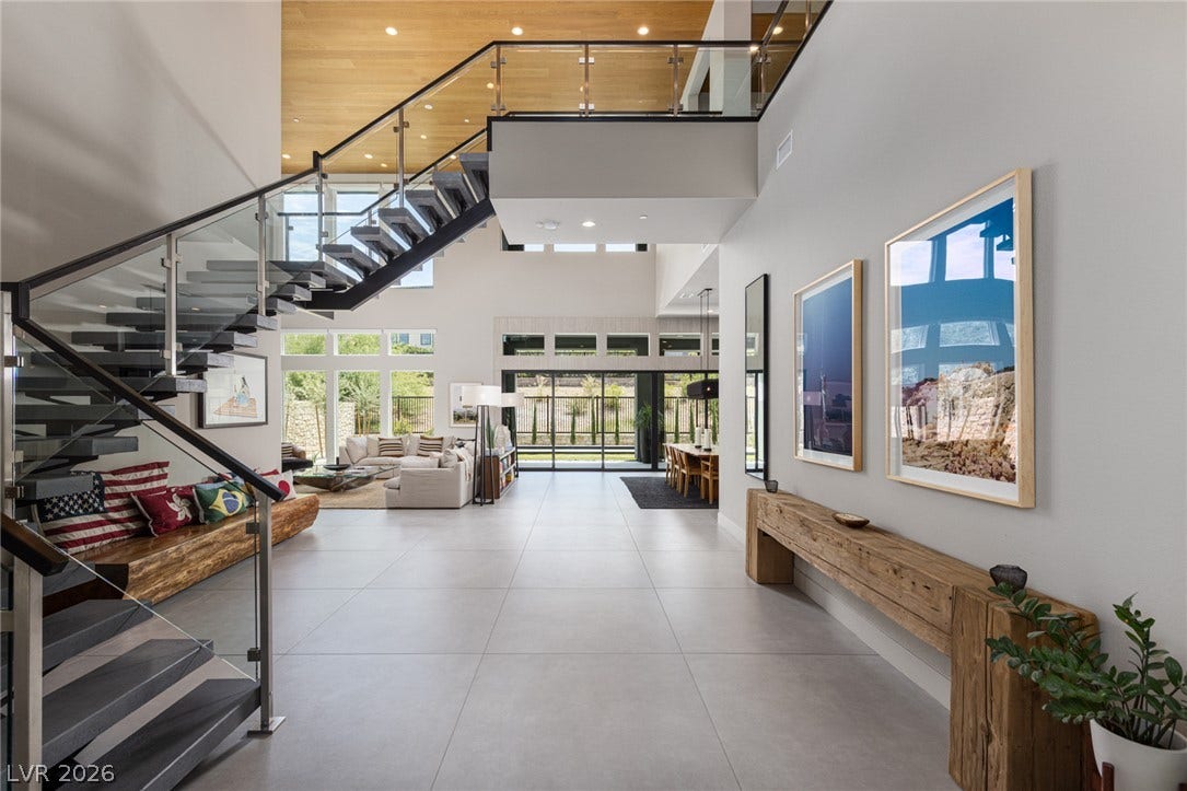 5216 Fading Sunset Drive, Las Vegas, NV 89135 A grand, open-concept living space features soaring ceilings, a modern glass staircase, and abundant natural light.