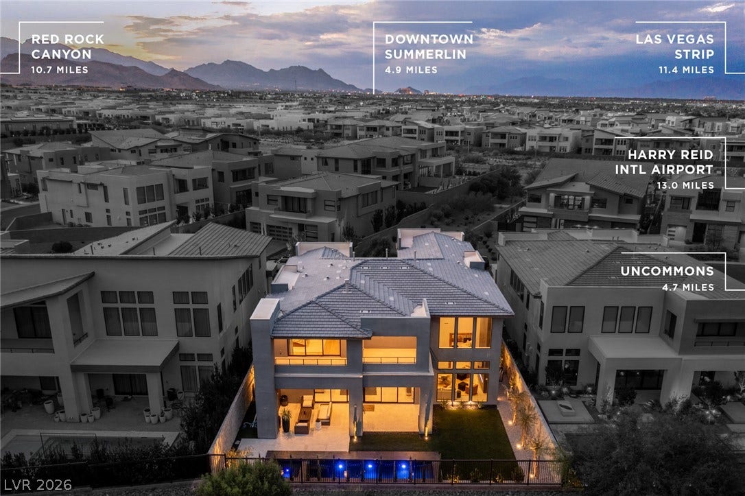 5216 Fading Sunset Drive, Las Vegas, NV 89135 An aerial perspective showcases a grand modern residence with an illuminated backyard, surrounded by a vibrant neighborhood.