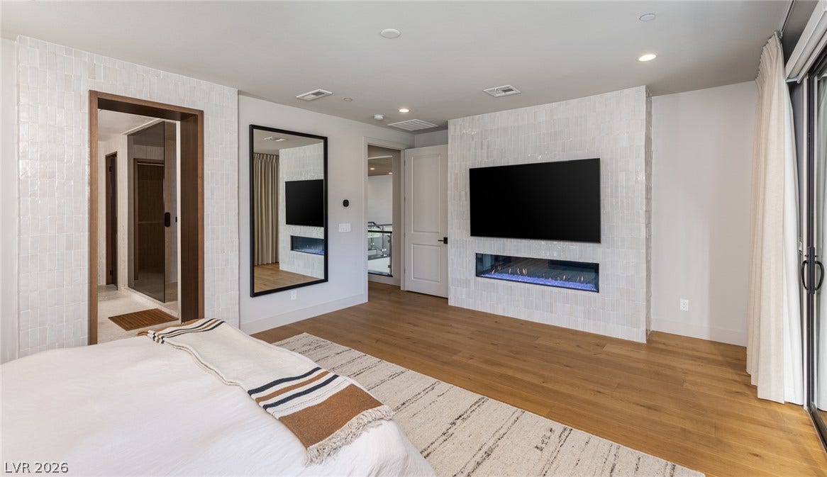 5216 Fading Sunset Drive, Las Vegas, NV 89135 Gleaming hardwood floors and a modern linear fireplace elevate this refined bedroom suite.