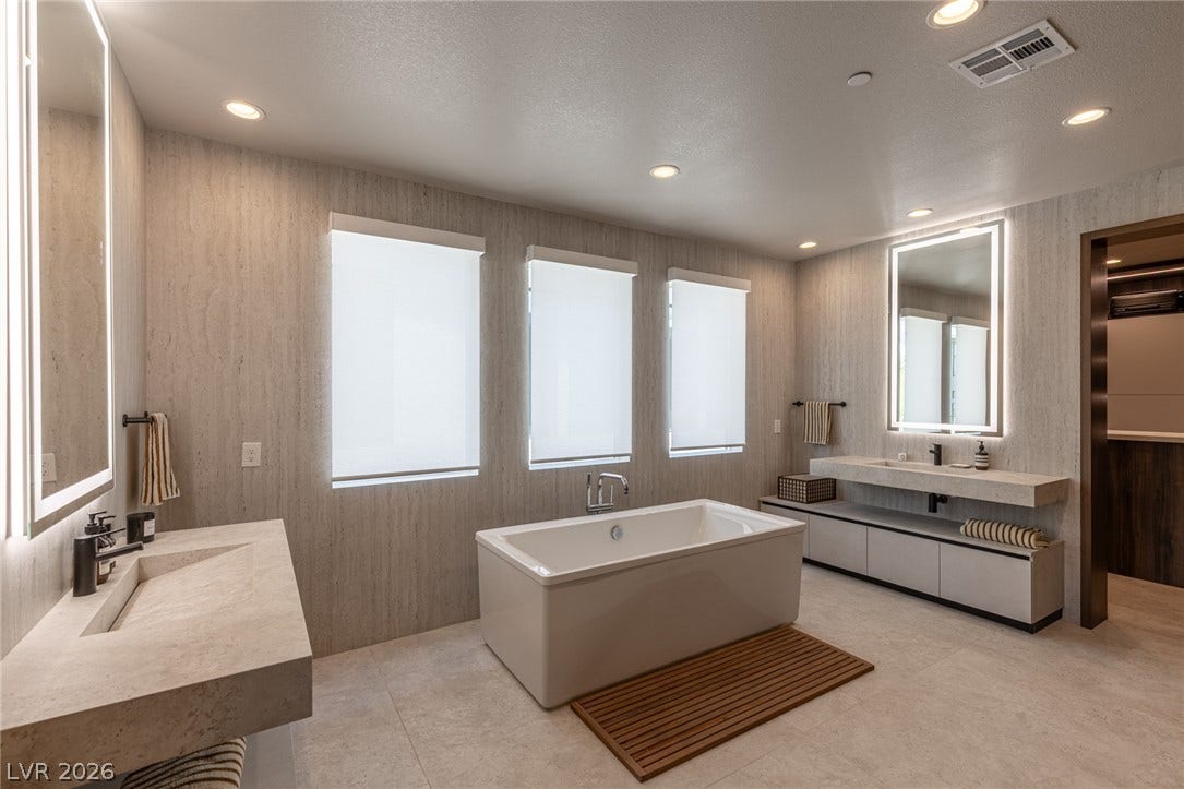 5216 Fading Sunset Drive, Las Vegas, NV 89135 Luxurious bathing retreat boasts a freestanding soaking tub and dual vanities with elegant tile flooring.