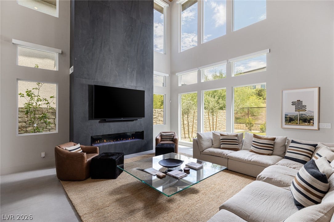 5216 Fading Sunset Drive, Las Vegas, NV 89135 A modern hearth with a linear fireplace anchors this living space, offering views of the natural landscape through tall windows.