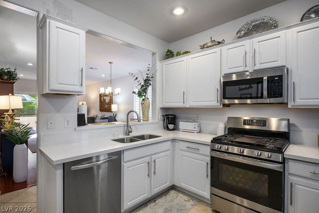 White cabinetry and stone countertops frame the modern cooking zone, opening to adjacent living spaces.