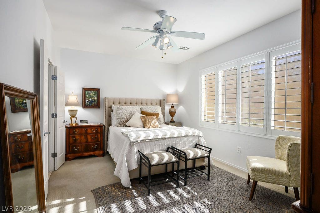 A tranquil sleeping space featuring carpeted flooring and large windows with plantation shutters.
