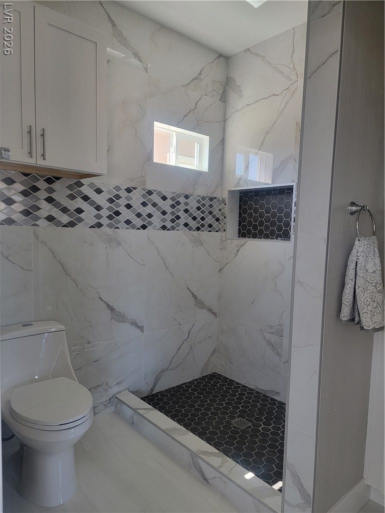 240 San Salvador Avenue, Henderson, NV 89002 Gleaming marble-look tiles line the floor and walls of this modern restroom space.