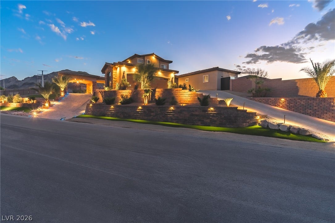 240 San Salvador Avenue, Henderson, NV 89002 Dramatic multi-tier stone retaining walls and integrated landscape lighting frame the custom hillside elevation.