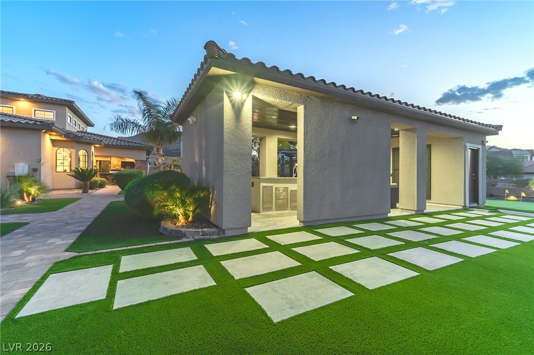 240 San Salvador Avenue, Henderson, NV 89002 An elegant pool house stands adjacent to manicured turf and architectural pavers under twilight skies.