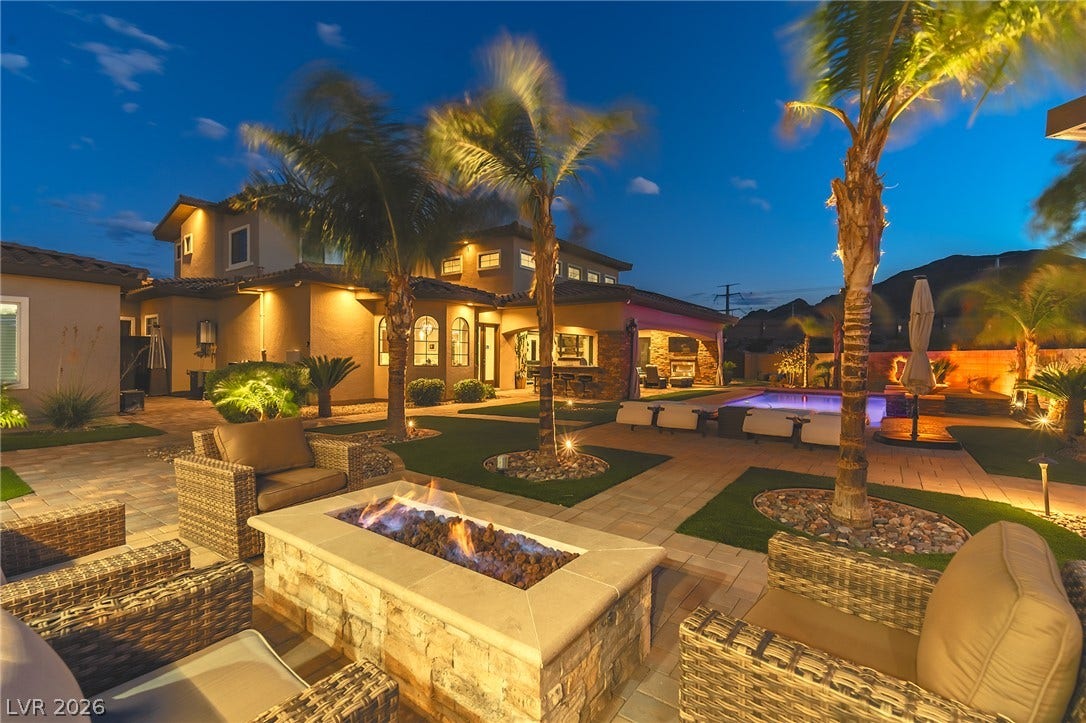 240 San Salvador Avenue, Henderson, NV 89002 Lush palm trees and stone-paved pathways frame a built-in outdoor fireplace and swimming pool.