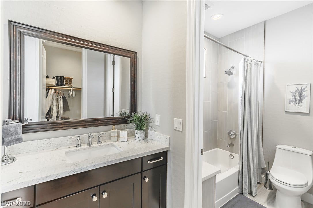 240 San Salvador Avenue, Henderson, NV 89002 Polished stone counters elevate this modern bathroom featuring a walk-in closet reflection.