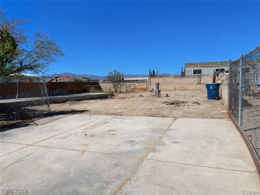 6196 Castlemont Avenue, Las Vegas, NV 89156 A spacious backyard area features a concrete slab and fencing against mountain backdrops.