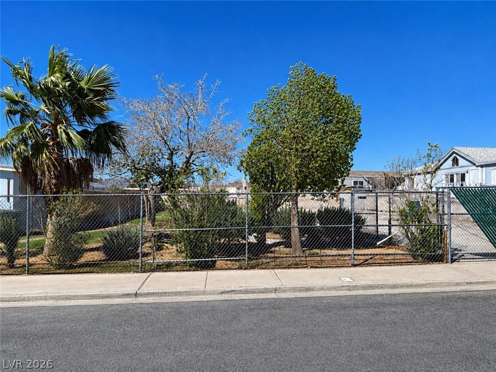 6196 Castlemont Avenue, Las Vegas, NV 89156 Mature trees and landscaping frame the property line behind a secure chain link fence.