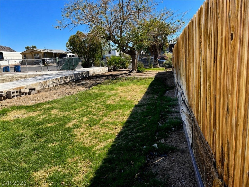 6196 Castlemont Avenue, Las Vegas, NV 89156 A sunny yard bordered by a wooden fence offers potential for outdoor activities.