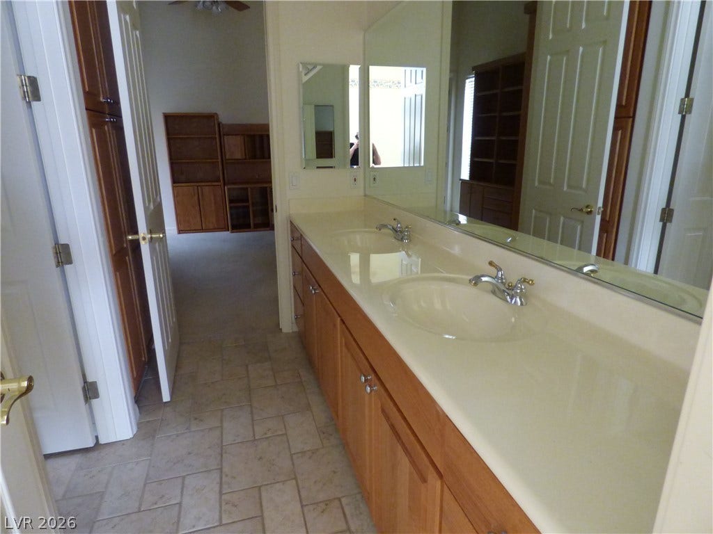 7695 Gilespie Street, Las Vegas, NV 89123 Gleaming tile floors complement a spacious double vanity with classic wood cabinetry. This is a Jack & Jill bath between the two separate bedrroms.