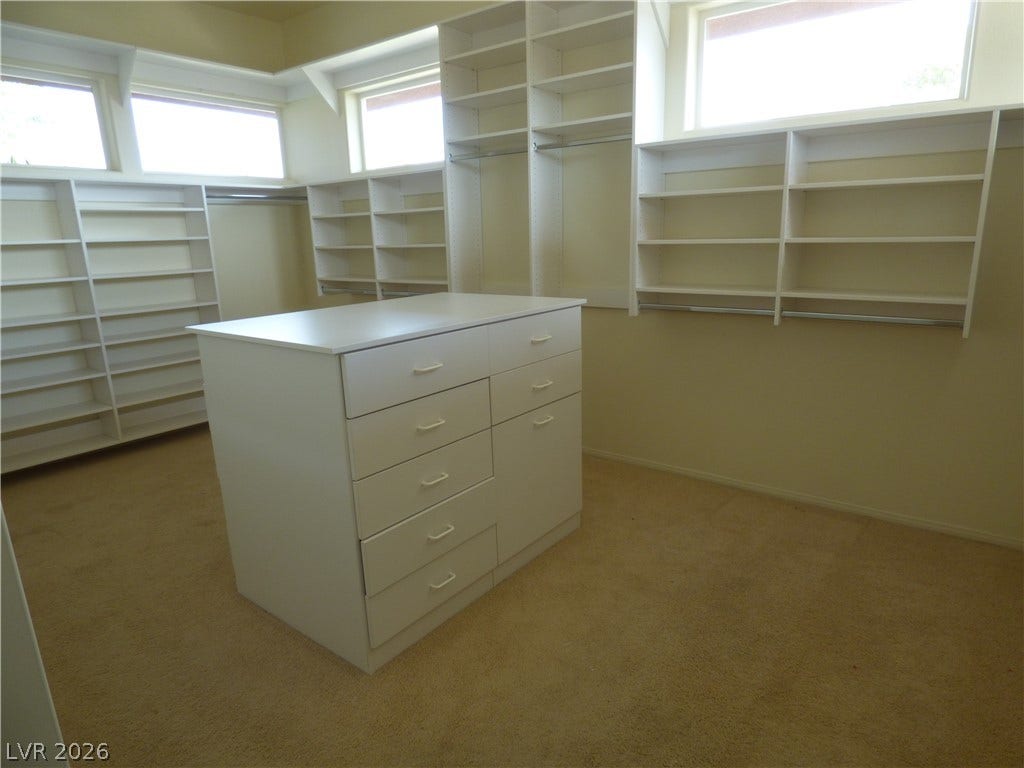 7695 Gilespie Street, Las Vegas, NV 89123 Ample built-in shelving and a central dresser island define this carpeted walk-in closet space.