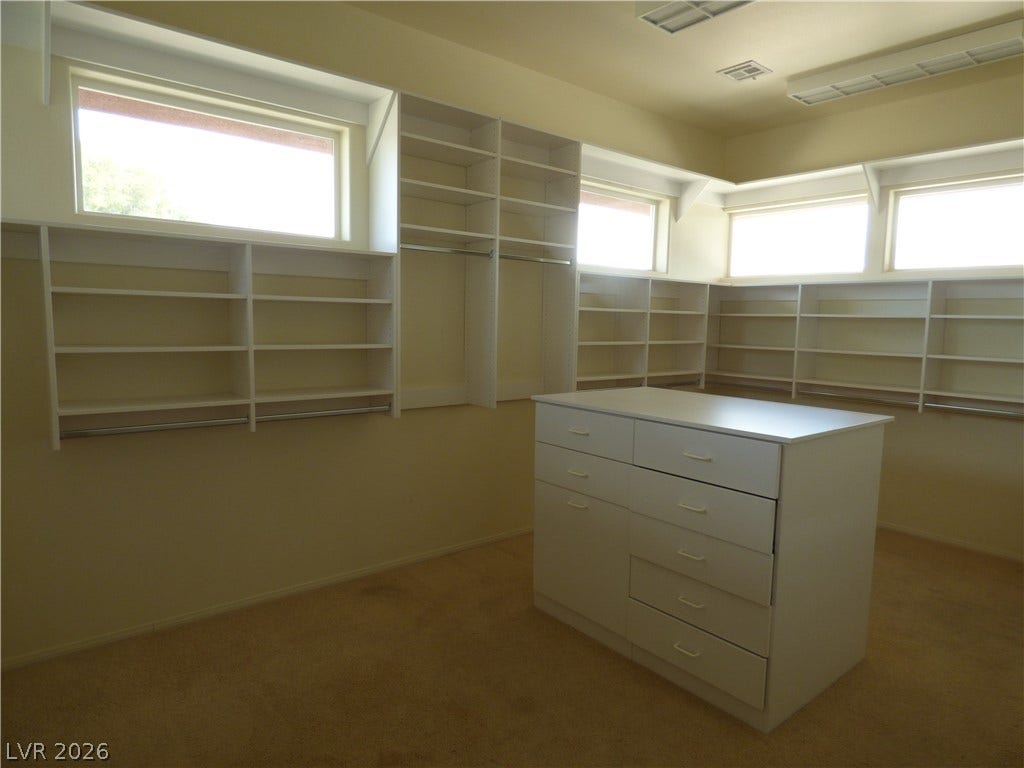 7695 Gilespie Street, Las Vegas, NV 89123 Ample built-in shelving, a central dresser island, and high clerestory windows define this primary bedroom closet.