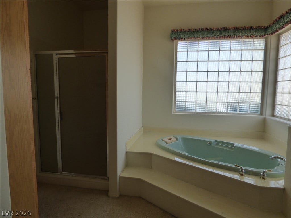 7695 Gilespie Street, Las Vegas, NV 89123 A spacious bathroom features a raised soaking jetted tub set against glass block windows.