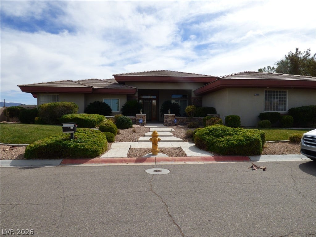 7695 Gilespie Street, Las Vegas, NV 89123 Manicured hedges frame a stone-lined walkway leading to the prominent entrance of this single-level home.