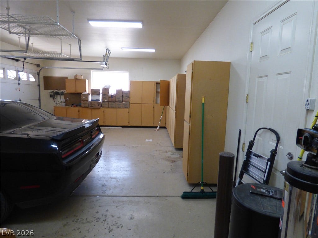 7695 Gilespie Street, Las Vegas, NV 89123 An organized garage space featuring concrete flooring, overhead racks, and extensive built-in cabinetry storage.