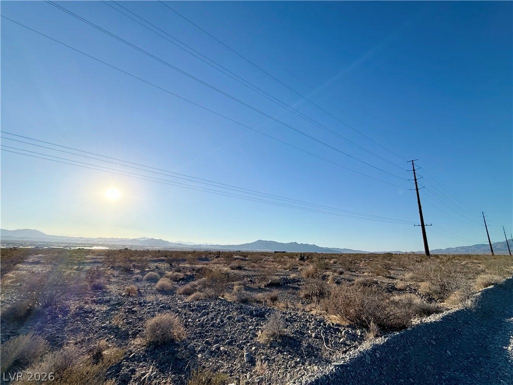 180 N Higley Road, Pahrump, NV 89060 Panoramic mountain views stretch across this expansive desert lot under a clear blue sky.