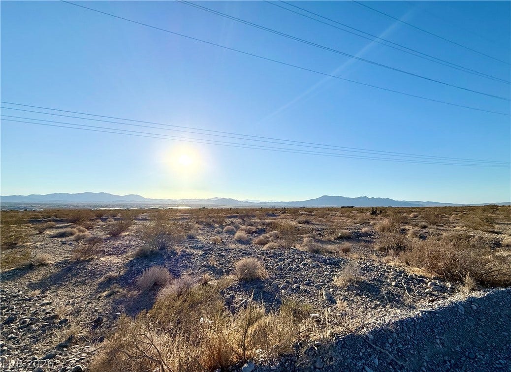 180 N Higley Road, Pahrump, NV 89060 Distant mountain ranges frame this expansive desert parcel under a clear, sunlit sky.