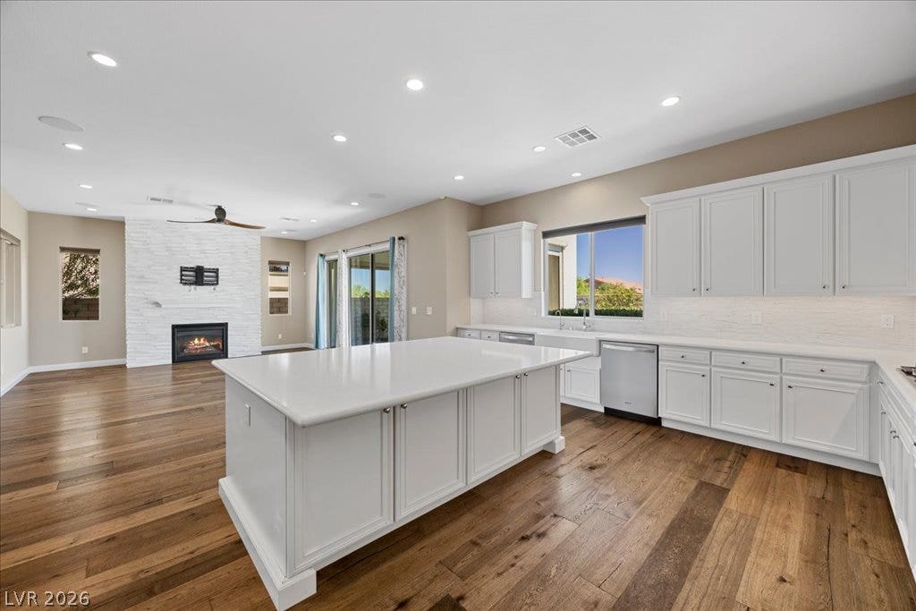 12021 Abbracci Avenue, Las Vegas, NV 89138 A well-lit kitchen with a spacious island flows into a living area with a stone-clad fireplace.