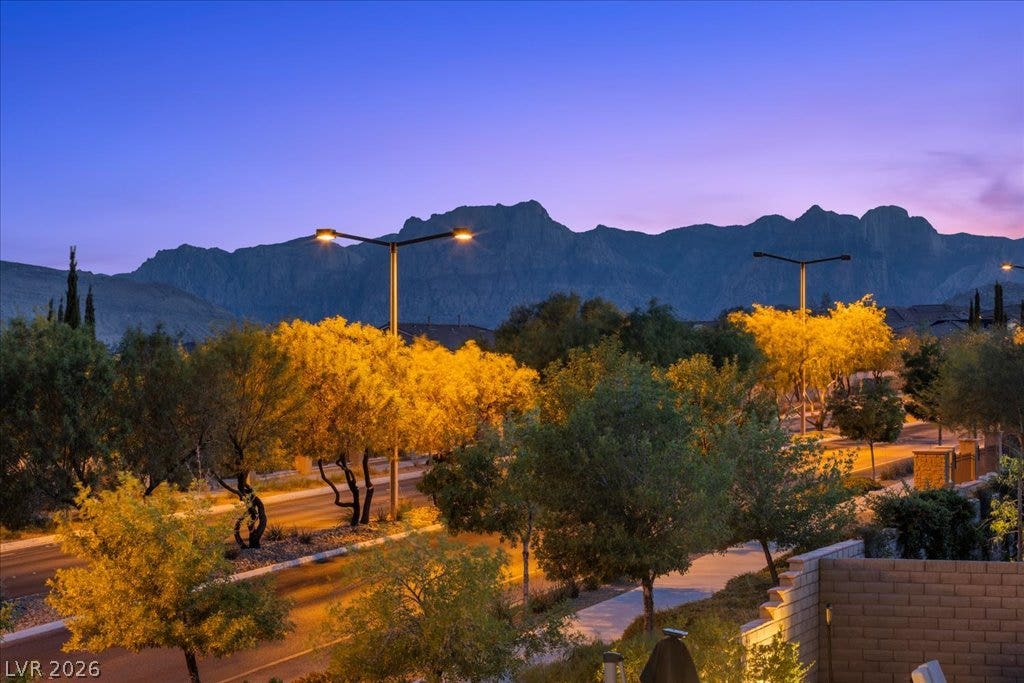 12021 Abbracci Avenue, Las Vegas, NV 89138 View from primary balcony Dramatic mountain vistas frame a well-lit street and meticulously landscaped common areas.