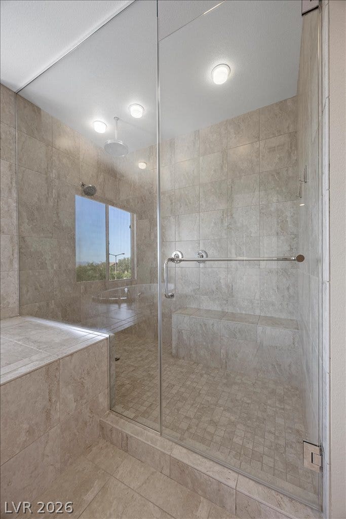 12021 Abbracci Avenue, Las Vegas, NV 89138 Step into a spacious, tiled shower with a built-in bench and glass enclosure.