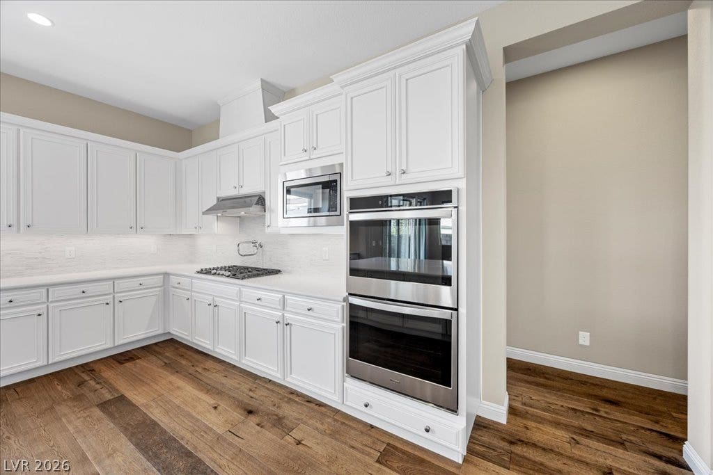 12021 Abbracci Avenue, Las Vegas, NV 89138 White cabinetry, stainless steel appliances, and rich wood flooring create a modern culinary space.