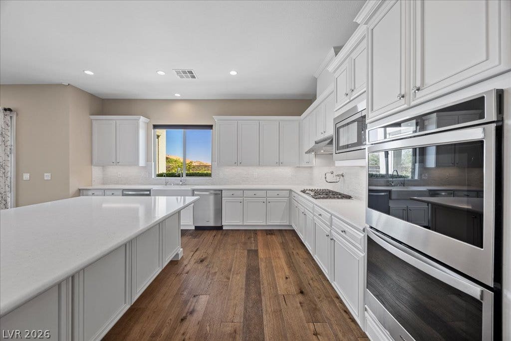 12021 Abbracci Avenue, Las Vegas, NV 89138 An inviting kitchen with pristine white cabinetry, rich hardwood floors, and a bright, functional island.