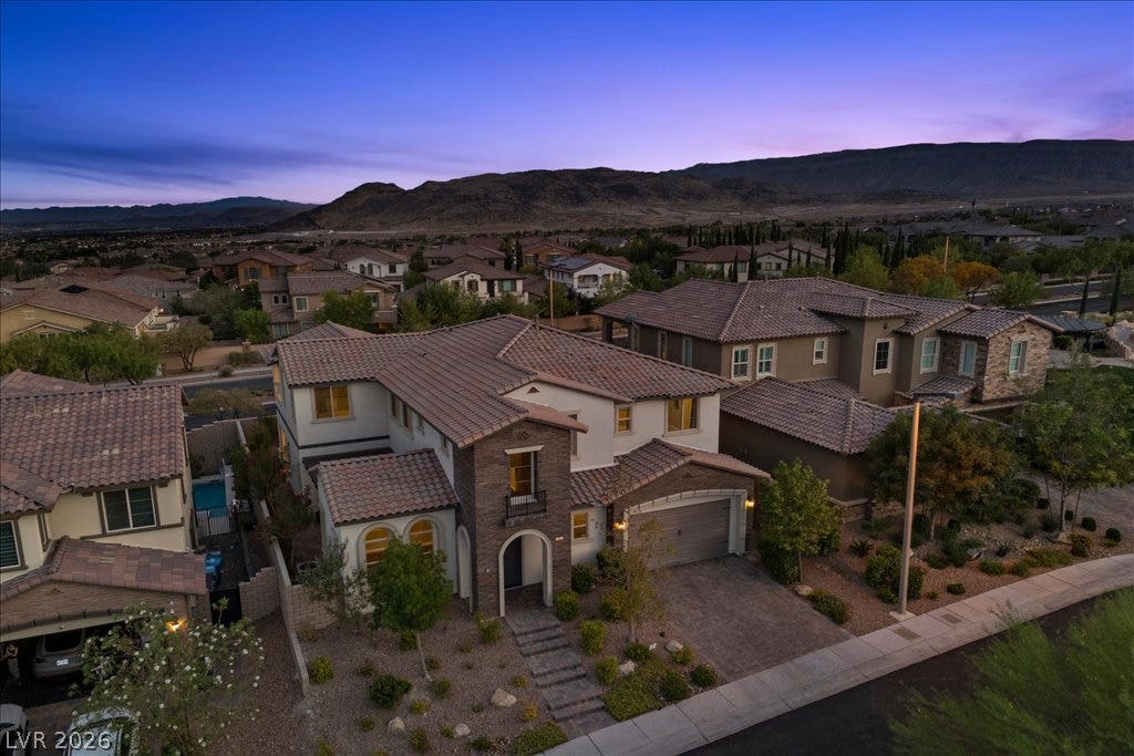 12021 Abbracci Avenue, Las Vegas, NV 89138 An aerial perspective reveals a contemporary residence nestled among rolling hills at dusk.