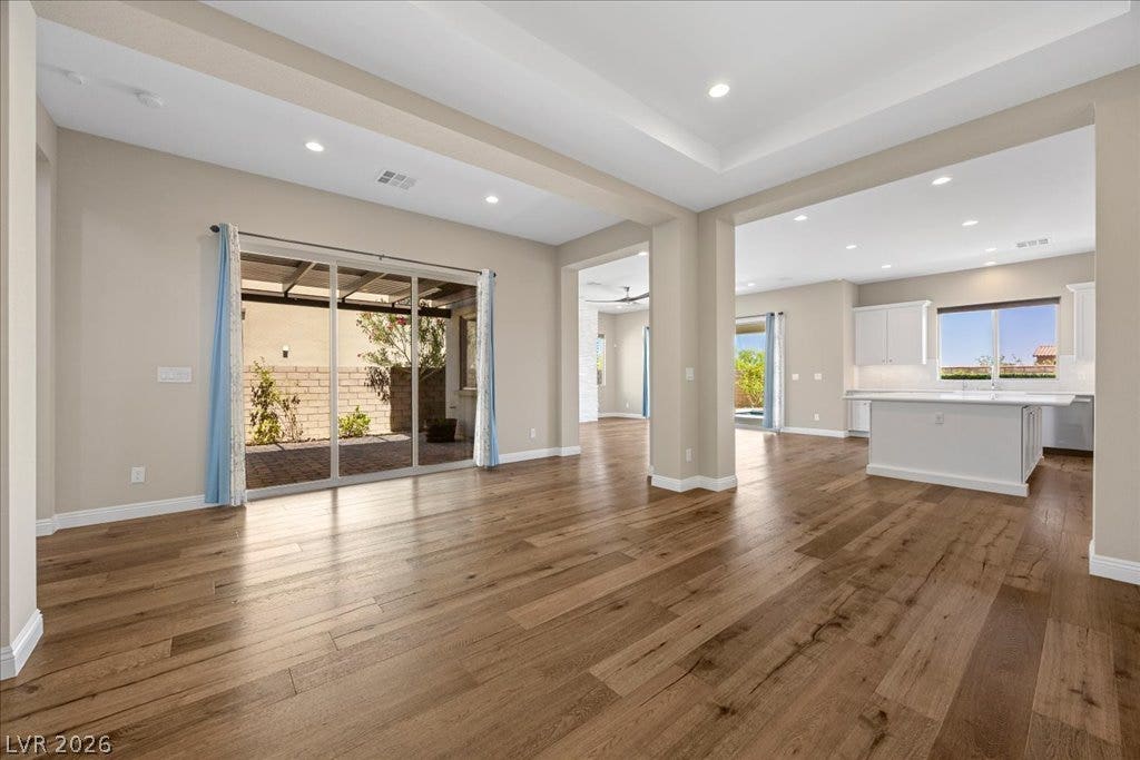 12021 Abbracci Avenue, Las Vegas, NV 89138 Hardwood floors stretch across this open-concept layout, connecting the living area to a bright kitchen and outdoor patio.