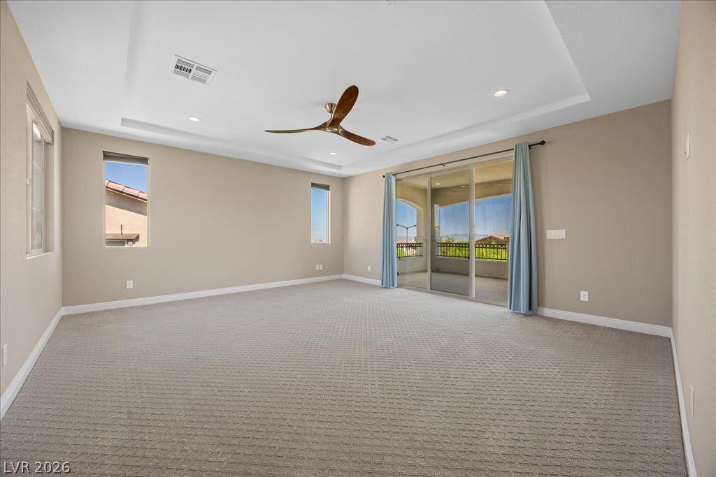 12021 Abbracci Avenue, Las Vegas, NV 89138 A spacious chamber features a recessed ceiling, ceiling fan, and sliding glass doors leading to a private balcony.