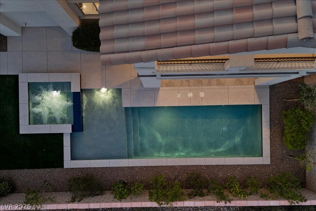 12021 Abbracci Avenue, Las Vegas, NV 89138 An aerial view captures the serene in-ground pool and an adjacent spa, illuminated by evening lights.