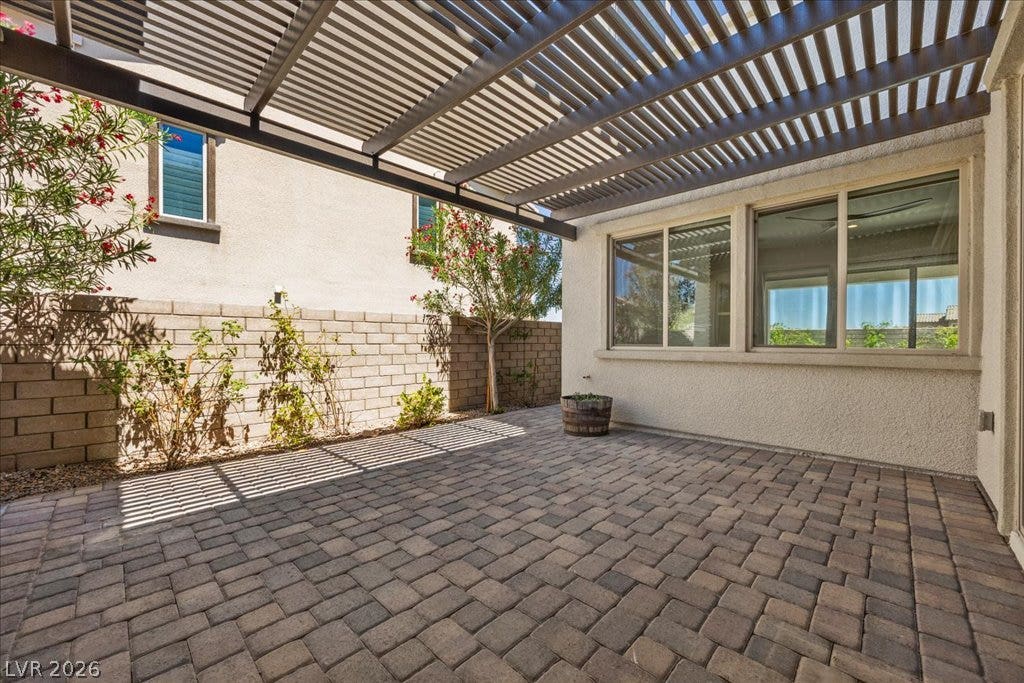 12021 Abbracci Avenue, Las Vegas, NV 89138 A spacious brick paver patio extends beneath a louvered pergola, perfect for outdoor gatherings.