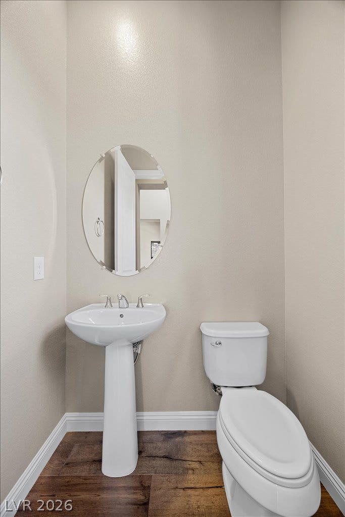12021 Abbracci Avenue, Las Vegas, NV 89138 A compact yet inviting half bathroom featuring a pedestal sink, toilet, and a chic oval mirror.