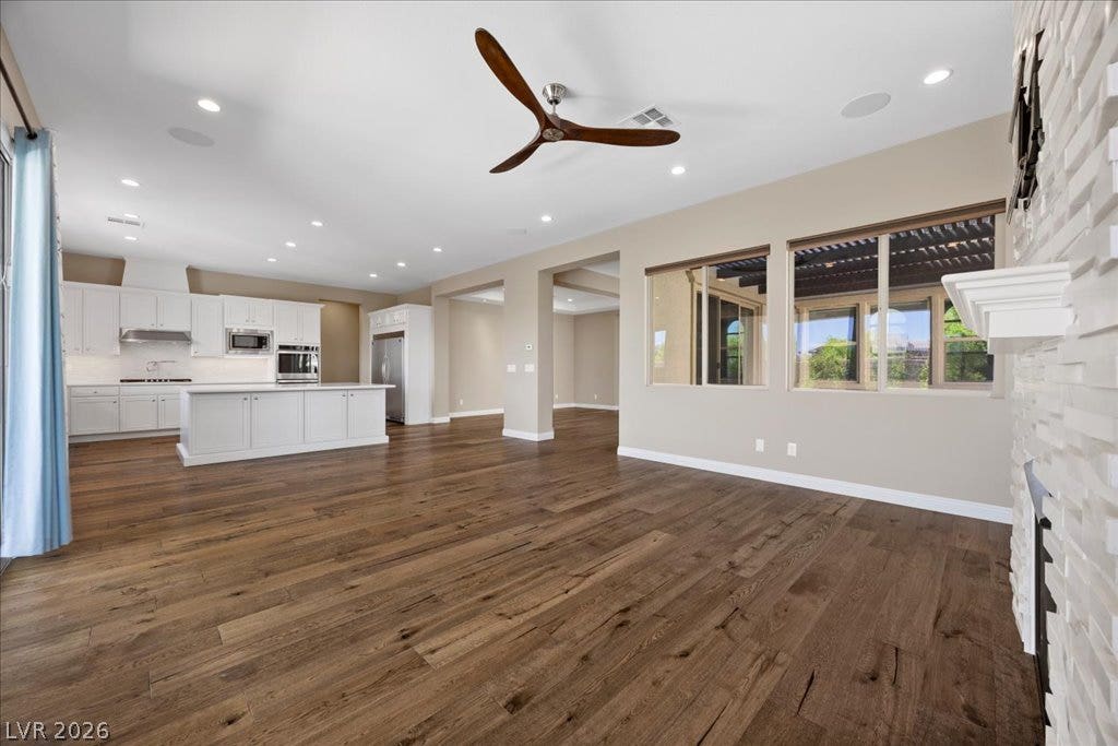 12021 Abbracci Avenue, Las Vegas, NV 89138 An open concept living area boasts rich hardwood flooring and a pristine white kitchen with built-in stainless steel appliances.