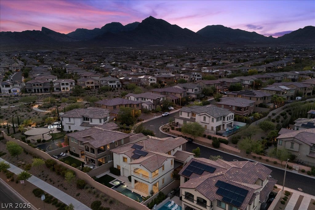 12021 Abbracci Avenue, Las Vegas, NV 89138 An aerial panorama showcases a residential community nestled against a dramatic mountain range at dusk.