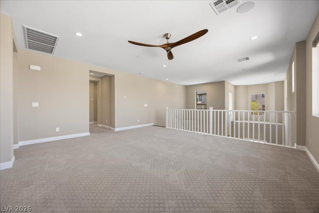 12021 Abbracci Avenue, Las Vegas, NV 89138 An airy loft with textured carpeting and a modern ceiling fan, offering an inviting secondary living space.