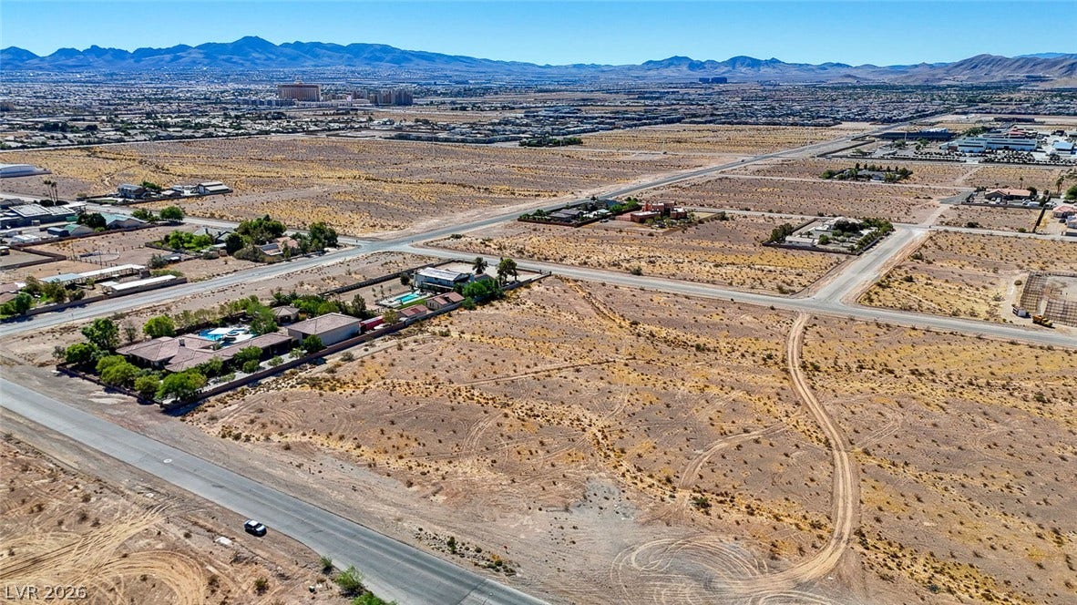 Pebble Road, Las Vegas, NV 89124 A vast desert landscape unfolds under blue skies with distant mountain ranges bordering the horizon.