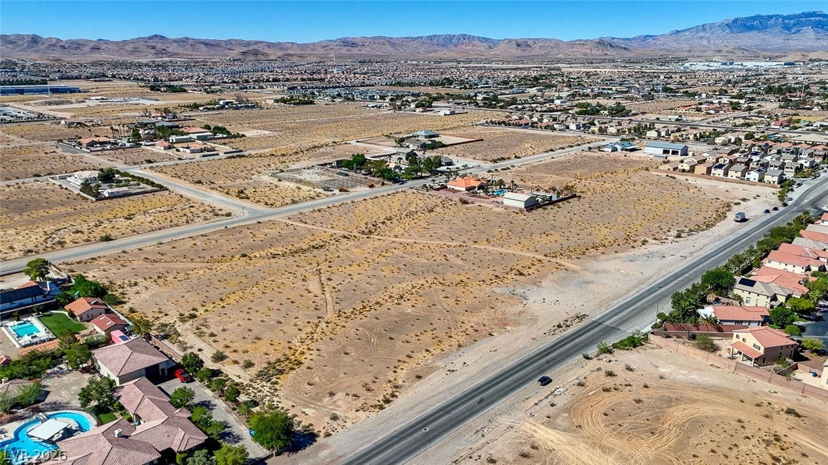 Pebble Road, Las Vegas, NV 89124 Vast desert parcels sit adjacent to paved roadways with mountain ridges spanning the horizon.