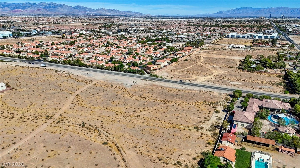 Pebble Road, Las Vegas, NV 89124 An expansive desert landscape borders a developed residential neighborhood beneath a clear blue mountain skyline.
