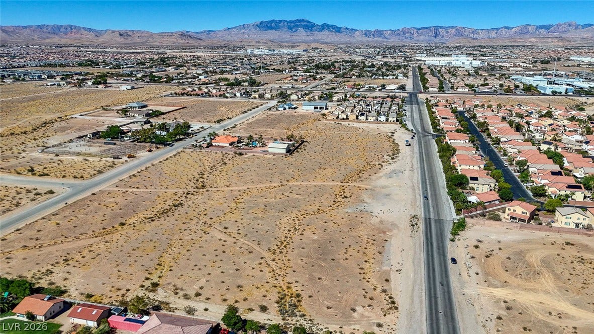 Pebble Road, Las Vegas, NV 89124 An expansive desert lot bordered by paved roads offers distant mountain views.