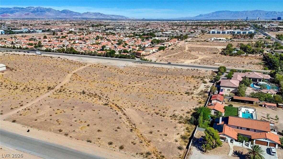 Pebble Road, Las Vegas, NV 89124 An aerial view showcases a vacant desert parcel positioned near residential neighborhoods and mountain ranges.