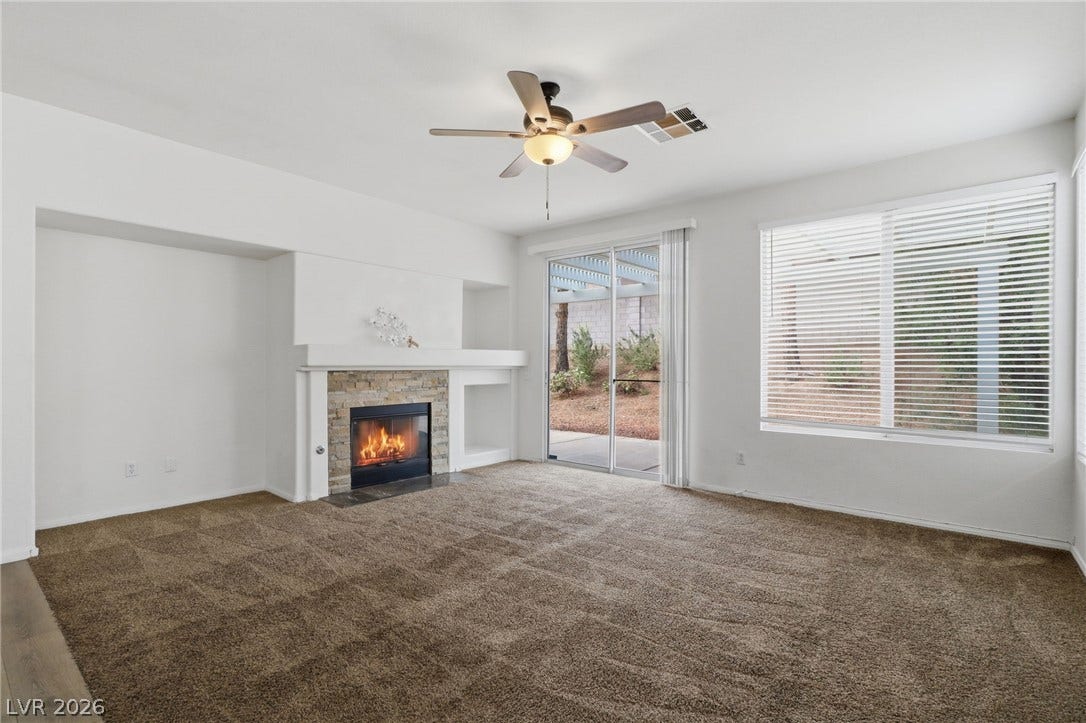 1891 Eagle Flight Lane, Henderson, NV 89012 A stone fireplace anchors the carpeted living space beneath high ceilings and large windows.
